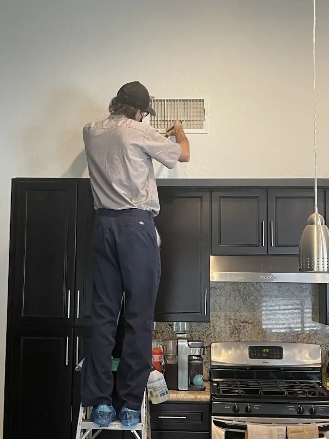 Technician inspecting an air vent during HVAC service in Big Rapids